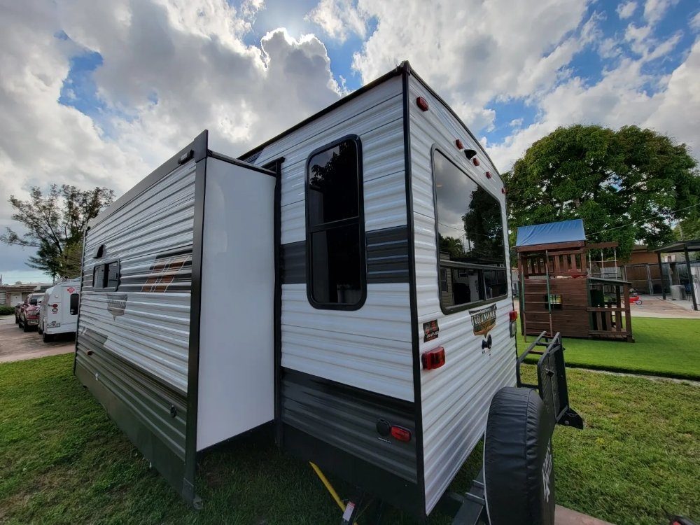 Travel trailer RV with tinted windows parked on grass