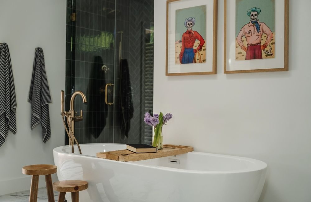 Primary bath with freestanding soaking tub, brass floor-mount filler and black shower glass