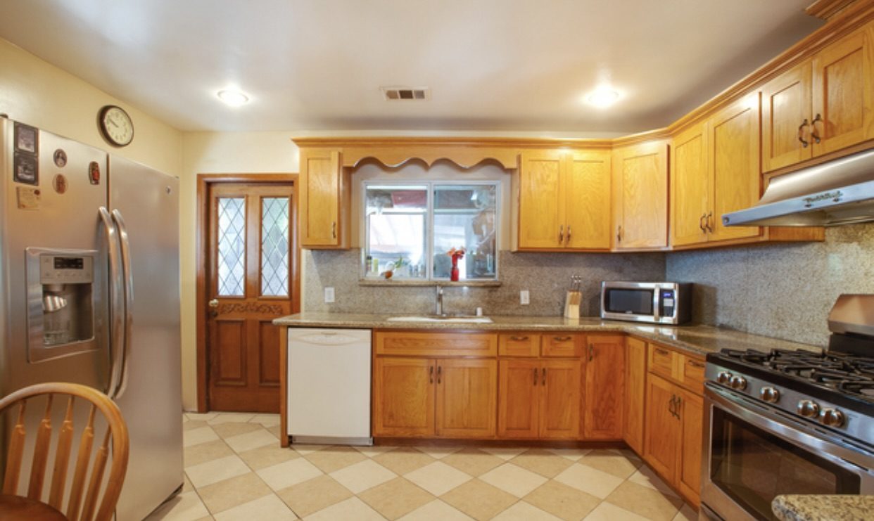Before: closed kitchen with oak cabinets, tile counters and a peninsula