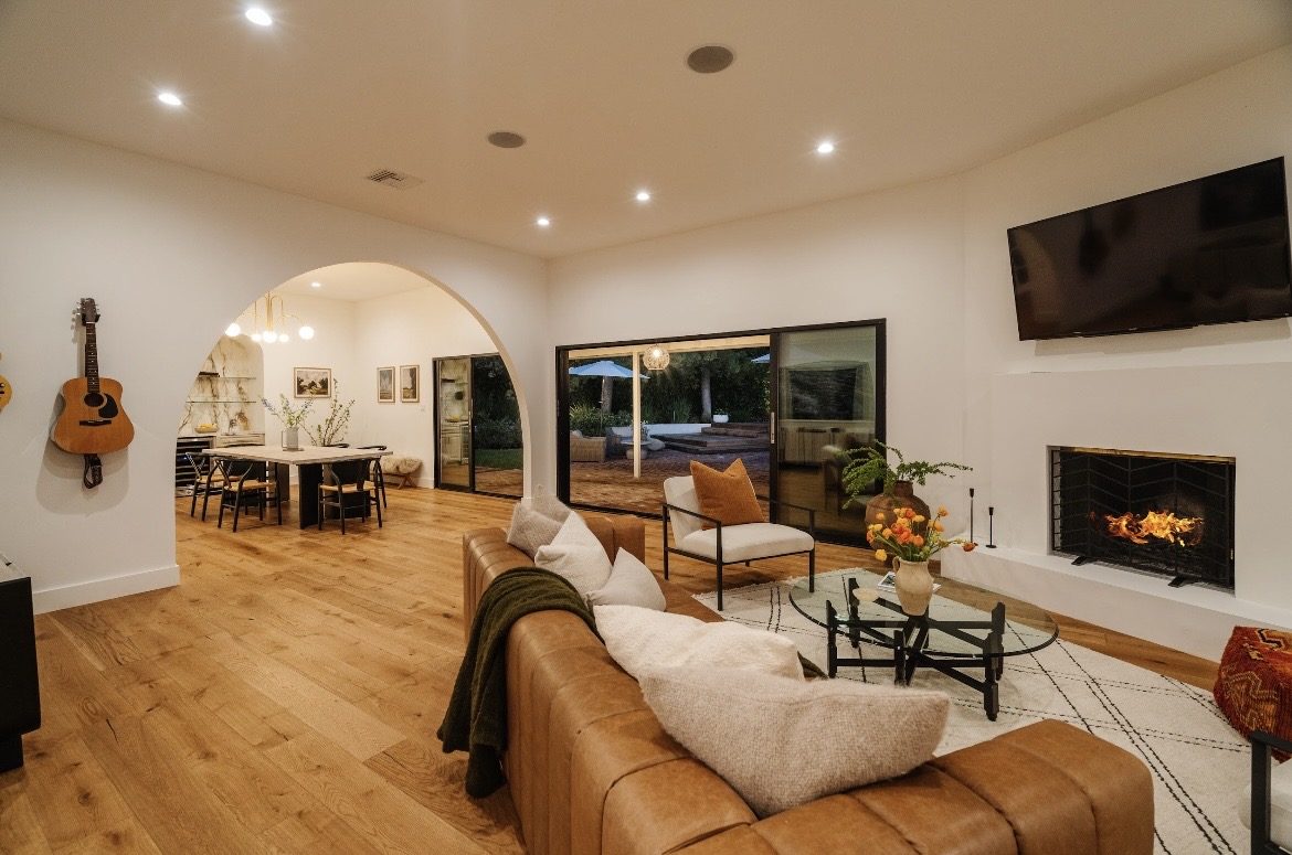 Open living and dining room with fireplace, oak floors and sliding doors to the pool