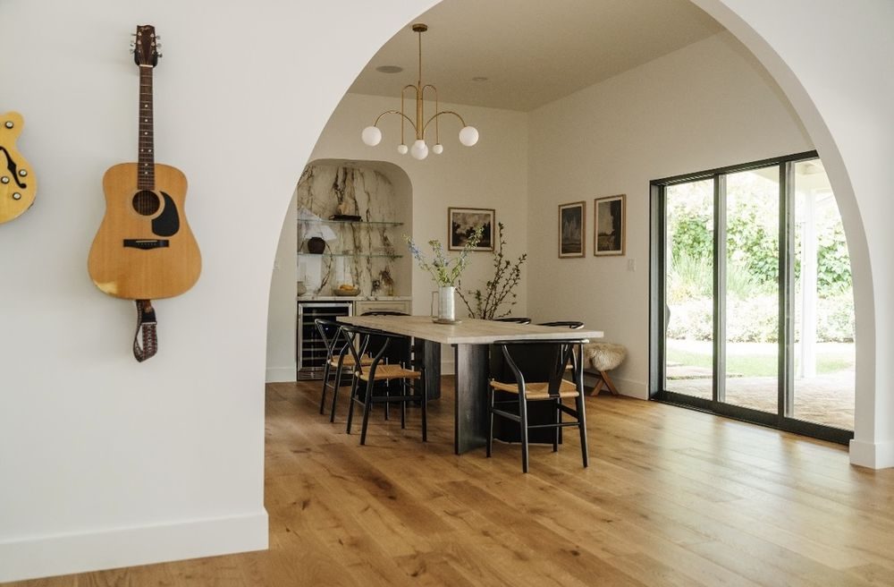 Dining room through a plaster arch with French doors opening to the yard