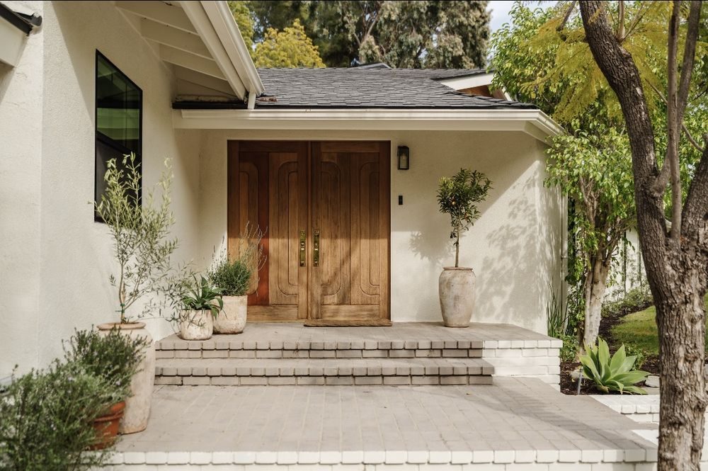 Front entry with double oak doors, plaster walls and stone steps under mature trees