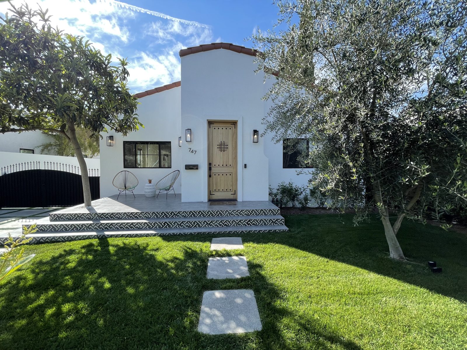 White Spanish Revival home with terracotta roofline, oak entry door and patterned tile steps renovated by D&H Contractors
