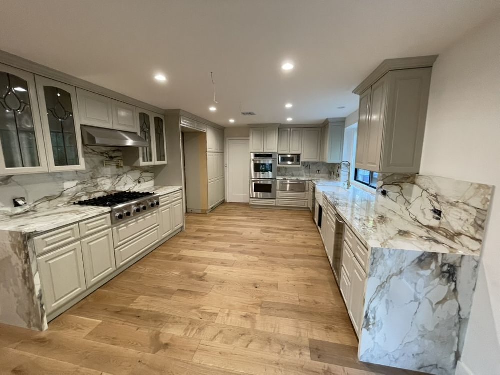 Kitchen with grey shaker cabinetry, quartzite counters and wide-plank oak floors