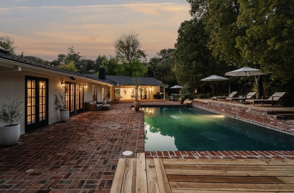 Brick pool terrace with new wood deck and French doors glowing at dusk