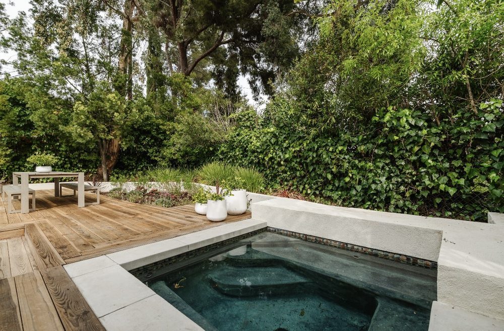 Plunge spa set into a wood deck surrounded by garden