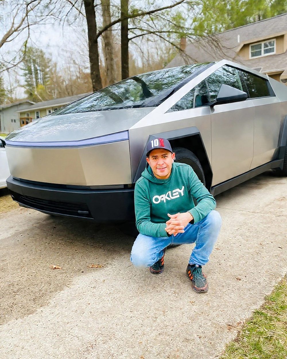 Manrique Hernandez kneeling beside a silver Tesla Cybertruck in a customer’s driveway after PPF and ceramic coating