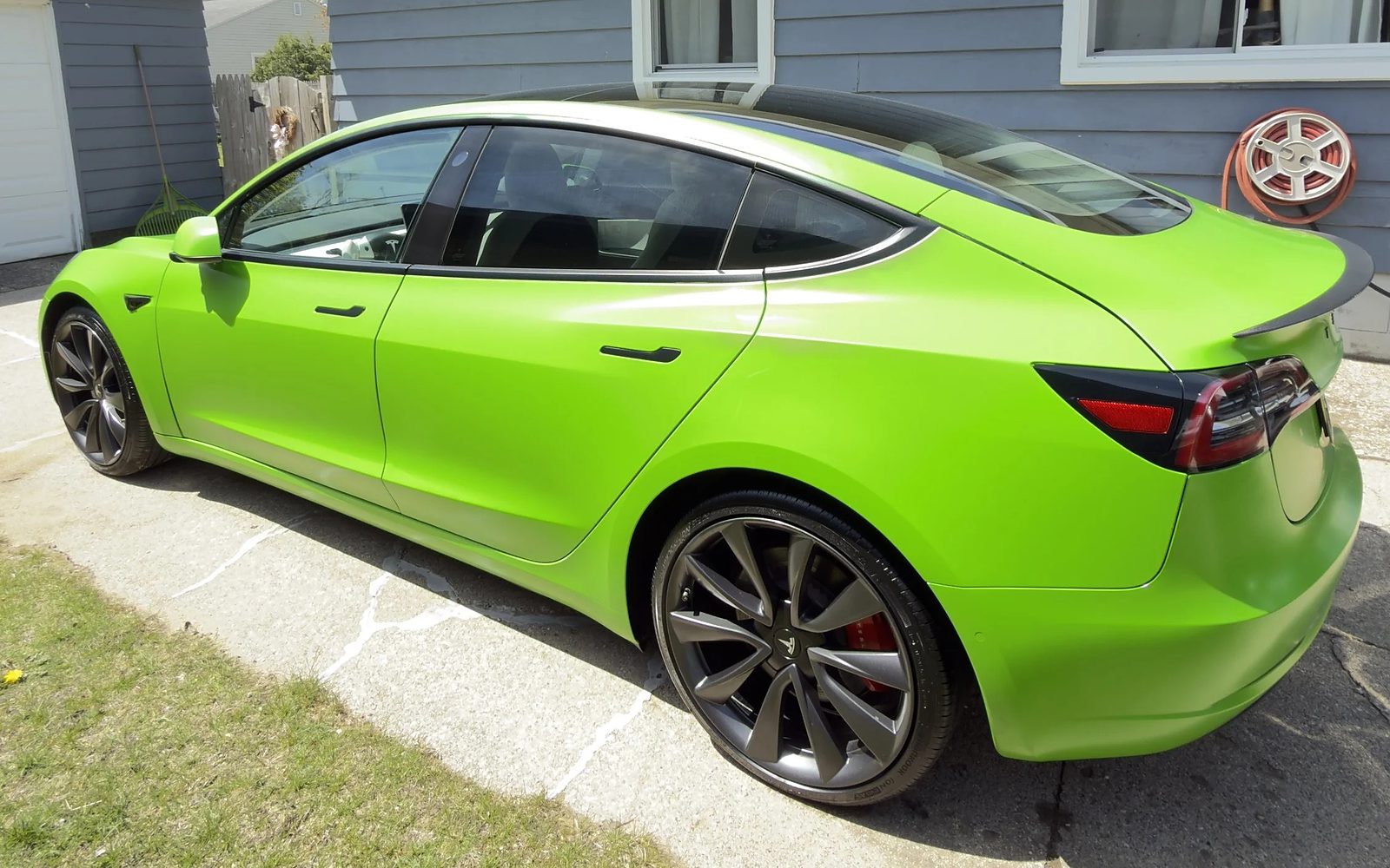Lime-green wrapped Tesla Model 3 with a fresh SunCoat ceramic coating in a Muskegon driveway