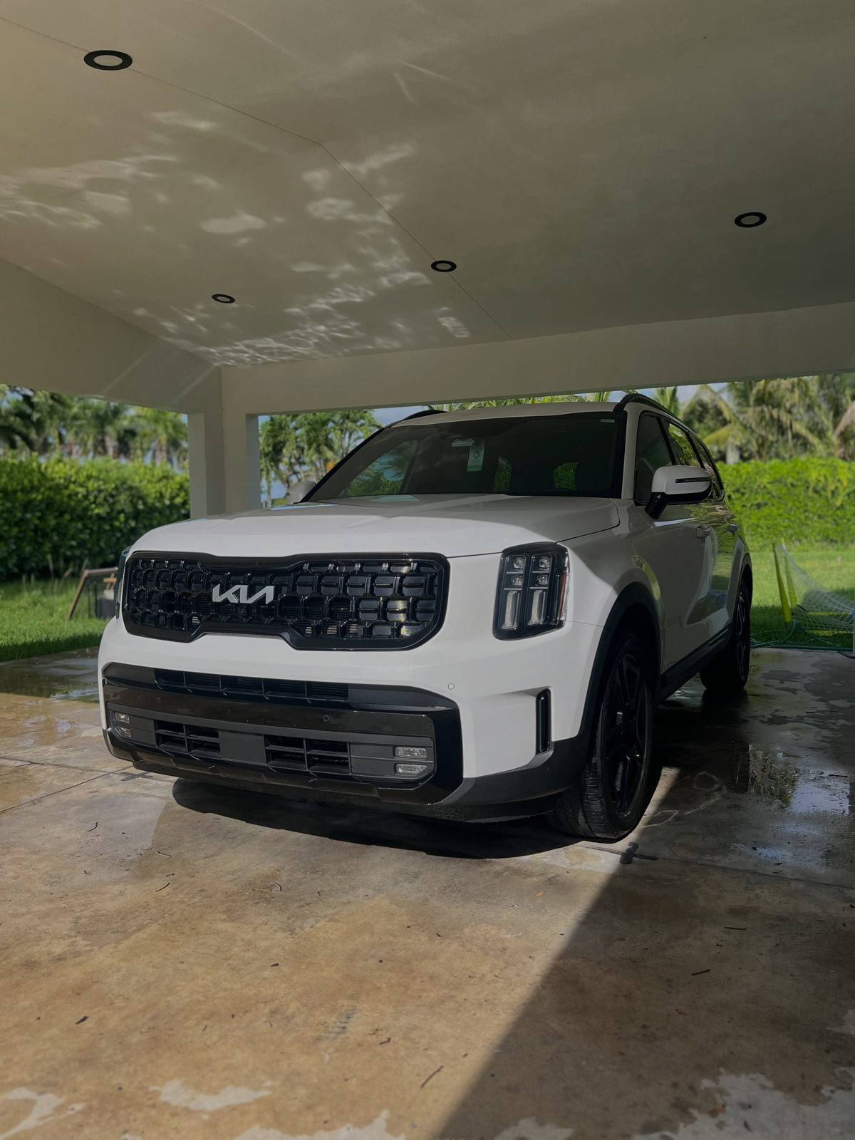 White Kia SUV washed in front of a garage