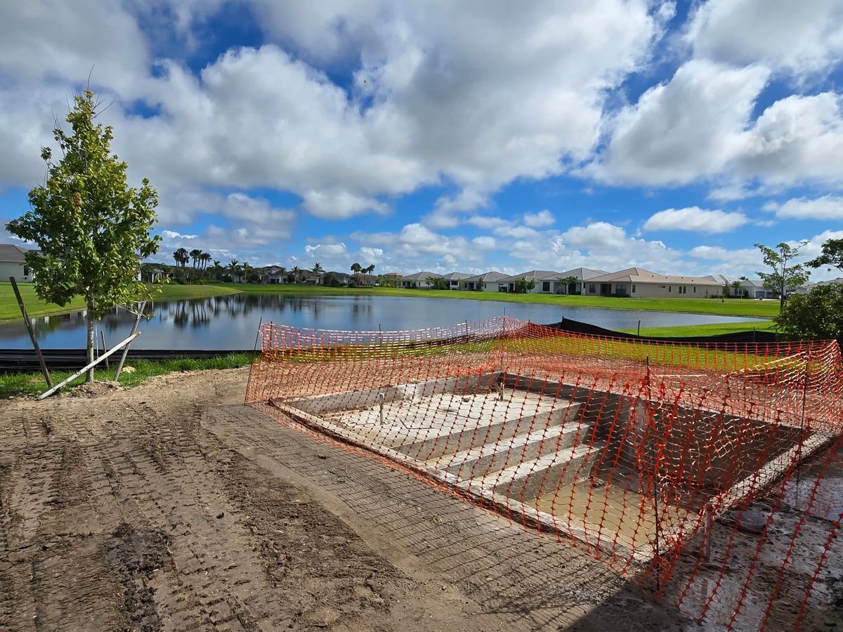 Graded lot around a new pool shell with lake behind