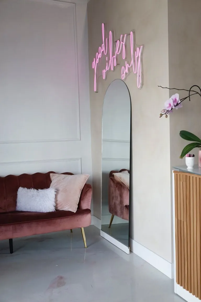 The Sovain lounge: a blush velvet loveseat, an arched mirror and a pink neon sign