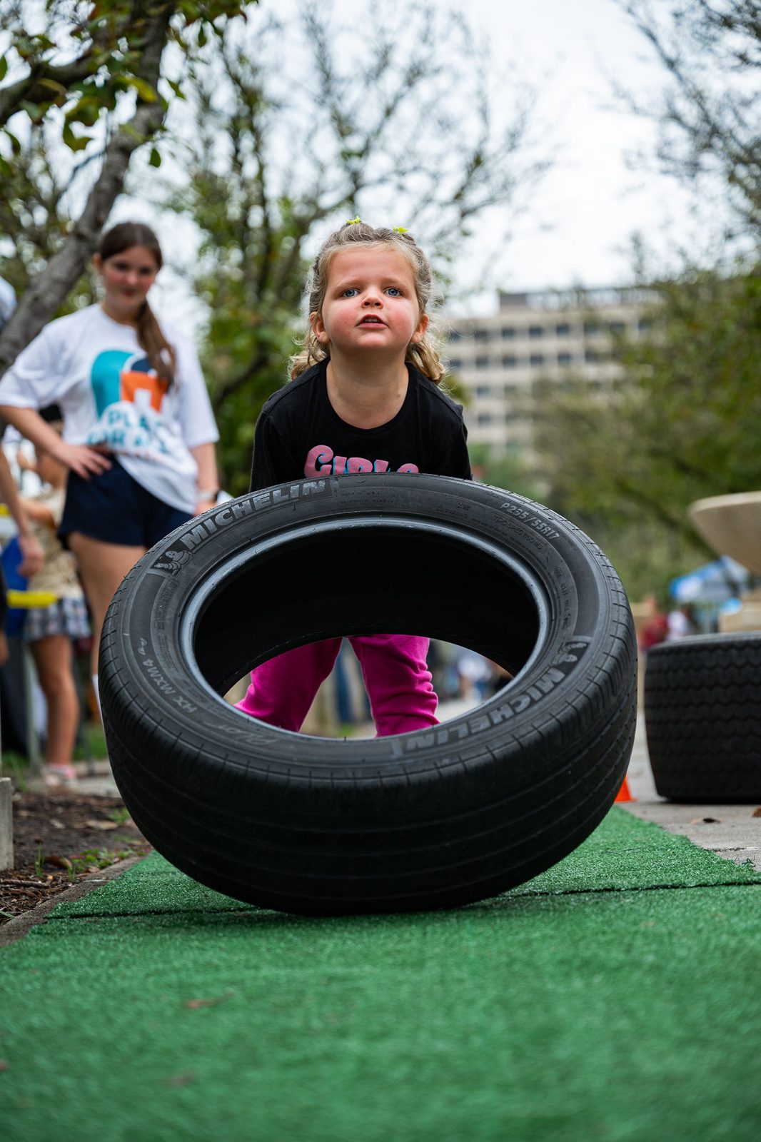 A young girl lifting a tire in the StrongKidz Zone