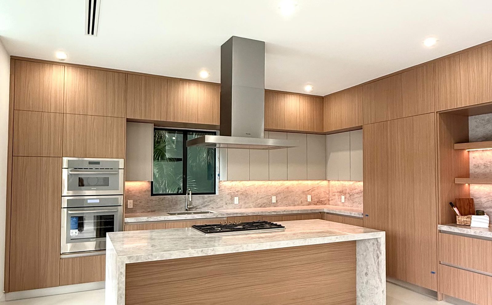 Kitchen remodel by Veloz Contractors: oak cabinetry, marble waterfall island and stainless hood