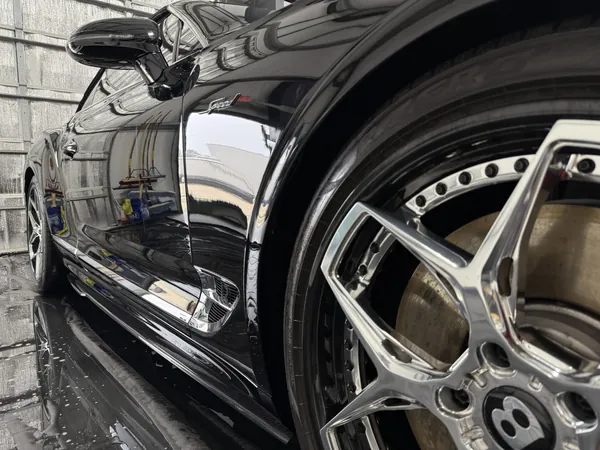 Rin y salpicadera de un Bentley negro con acabado mojado