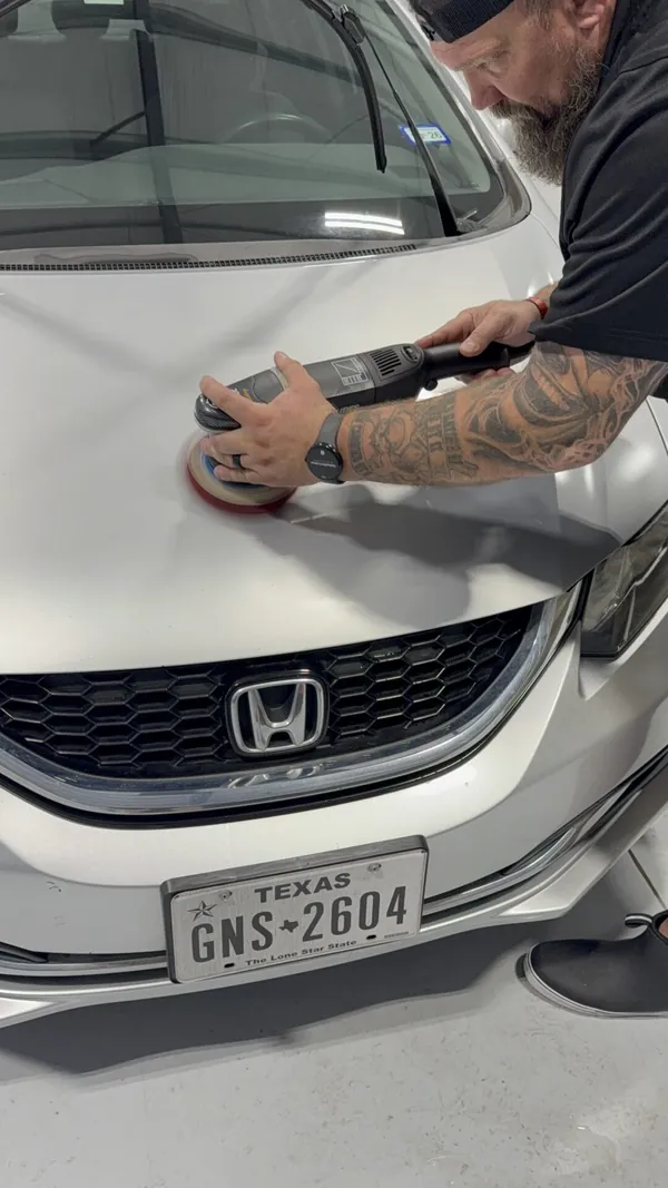 Técnico puliendo el cofre de un Honda blanco