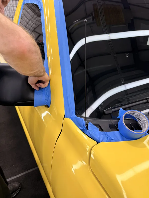 Enmascarando el borde de la puerta de un carro amarillo antes de pulir