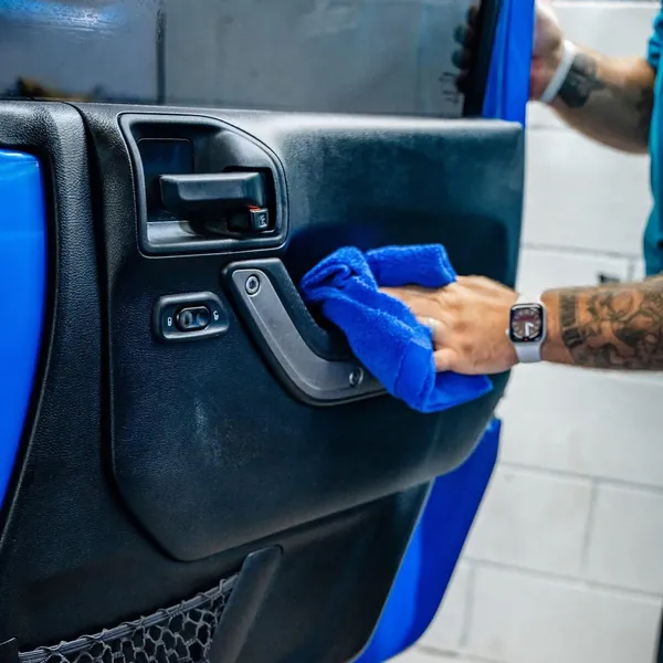 Técnico limpiando el panel de la puerta de un Jeep azul