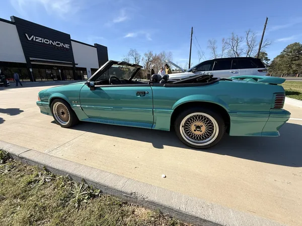 Mustang Fox-body convertible verde azulado afuera del taller