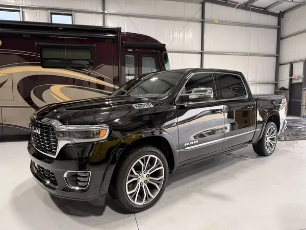 RAM 1500 negra con una casa rodante atrás en el taller