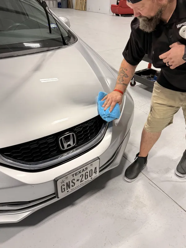 Técnico limpiando el cofre de un Honda blanco